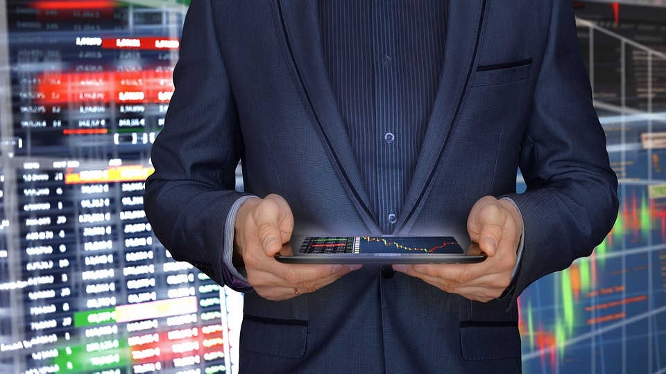 pattern day trader with ipad in front of trading screens